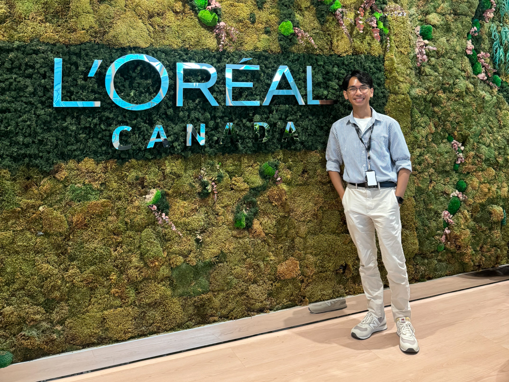 Jared Salvador smiling in front of a vertical garden wall featuring the L’Oréal Canada logo.