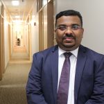 Jithan Sreedharan stands in a hallway at the College of Rehabilitation Sciences.