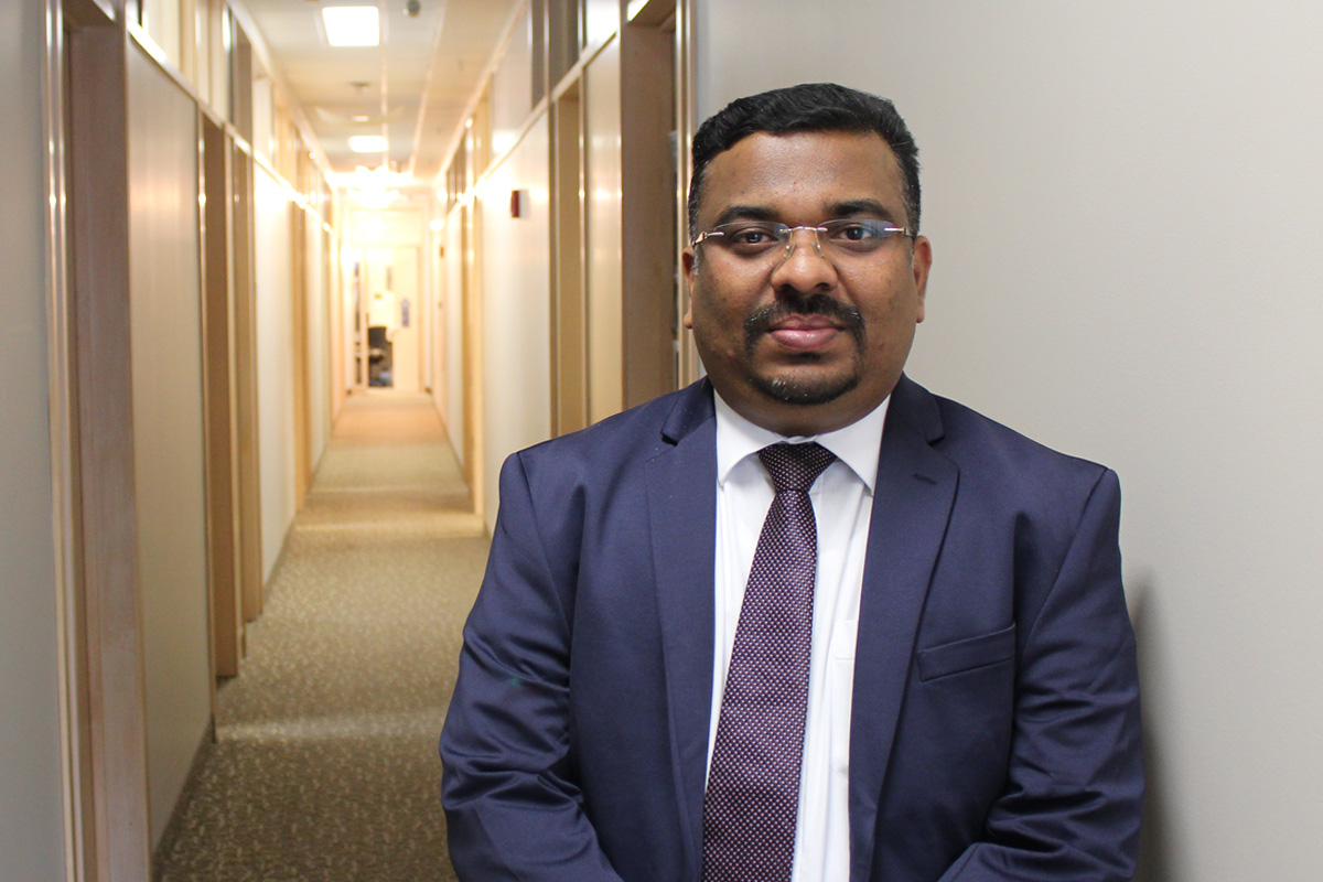 Jithan Sreedharan stands in a hallway at the College of Rehabilitation Sciences.
