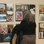 A person stands in front of collaged photos at a photography exhibit.