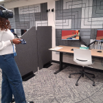 A student using a VR headset with art on computers in front of them