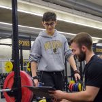 Adam Stevenson kneeling as he works with a Bisons student-athlete